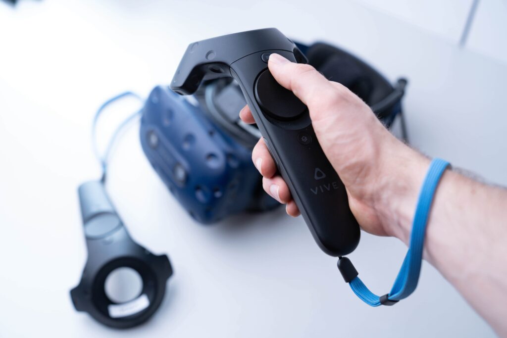 Osoba trzymająca kontroler do gier z goglami VR w tle